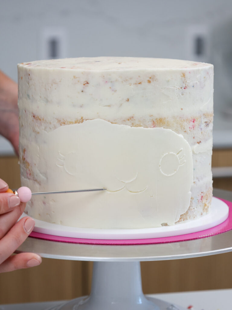 image of a llama face being outlined on a cake with a toothpick