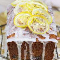 image of a blackberry lemon bread drizzled with lemon glaze and topped with candied lemons