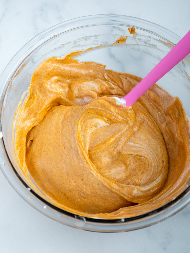 image of whipped cream being folded into no bake pumpkin cheesecake batter