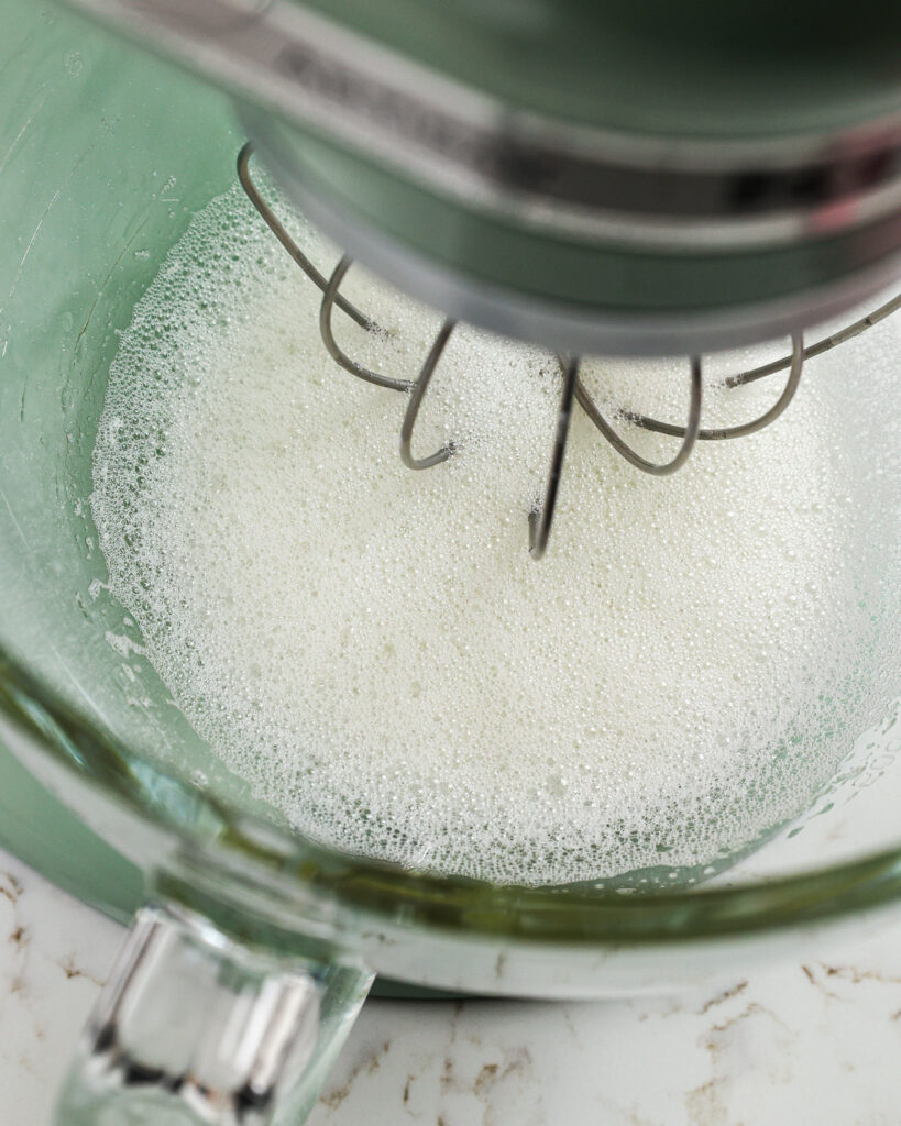 image of egg whites that have been whipped to make small bubbles on the top before adding in the sugar to make french meringue