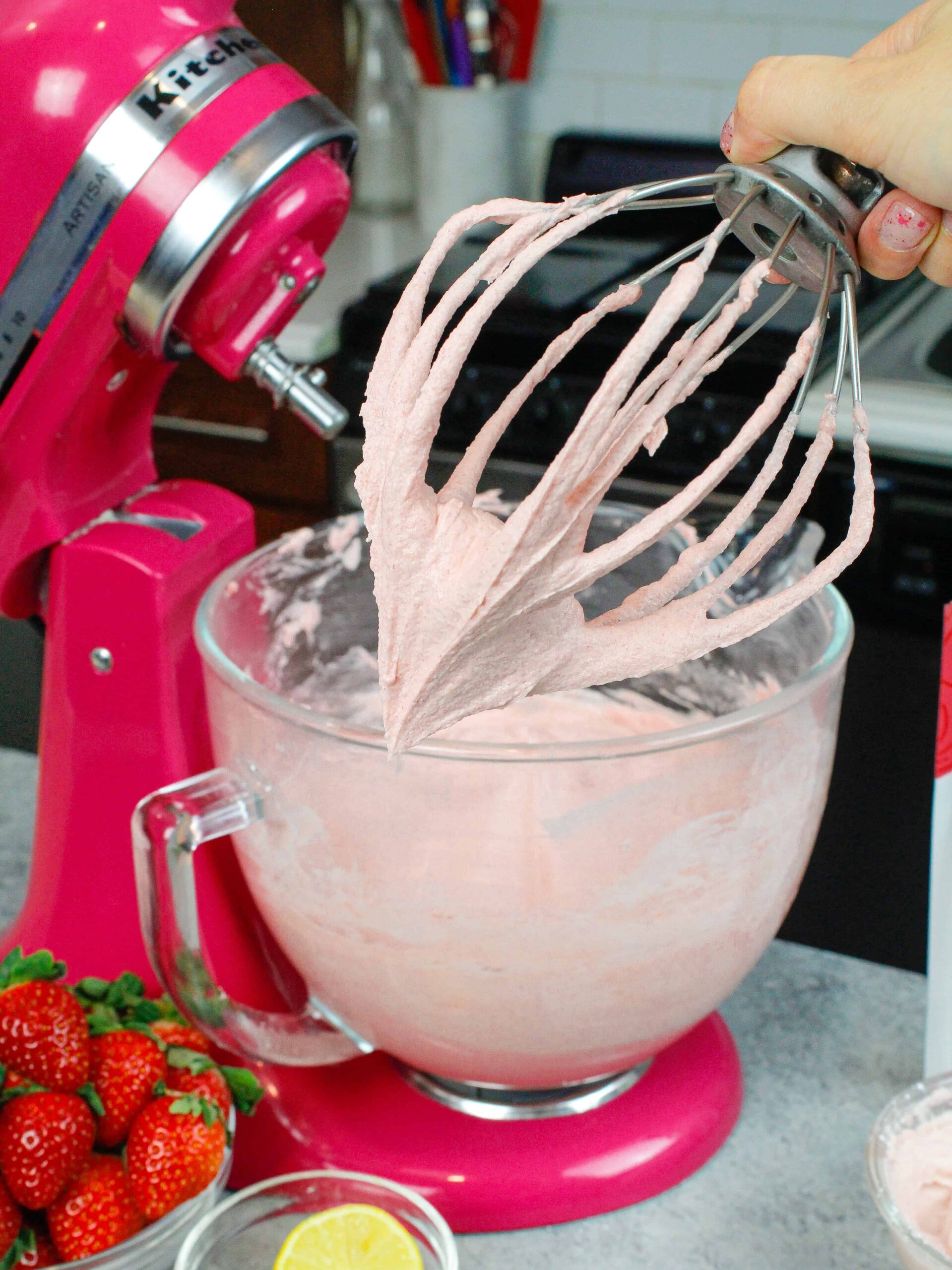 image of strawberry buttercream on whisk attachment with kitchenaid mixer in the background