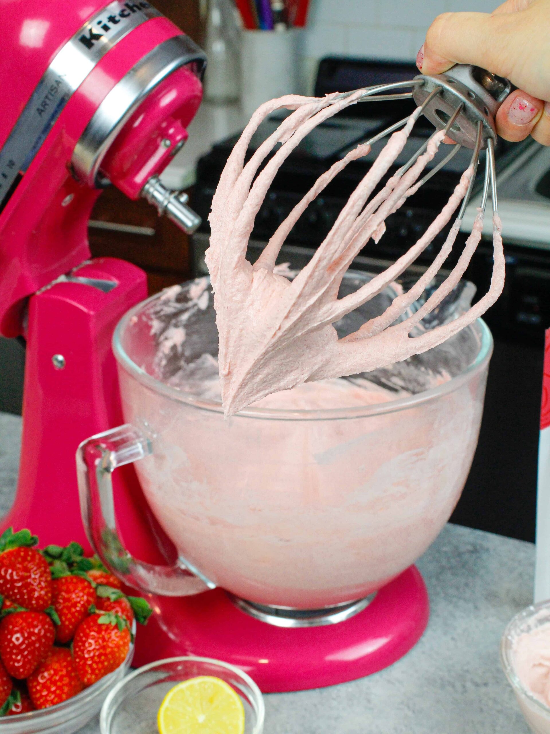 image of the best strawberry buttercream on whisk attachment with kitchenaid mixer in the background