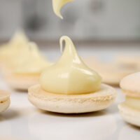 image of white chocolate ganache that's been piped onto a white macaron shell