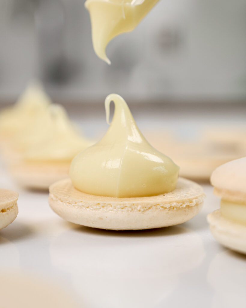 image of white chocolate ganache that's been piped onto a white macaron shell